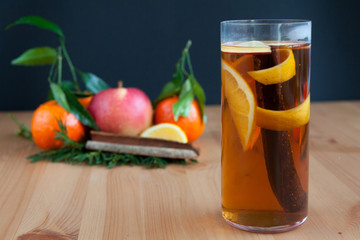 Glass with Seasonal warming drink.Cinnamon,lemon zest and some fruits.