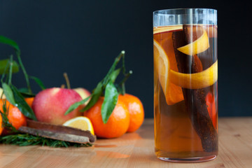 Glass with Seasonal warming drink.Cinnamon,lemon zest and some fruits.
