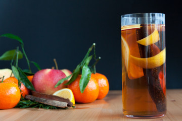 Glass with Seasonal warming drink.Cinnamon,lemon zest and some fruits.