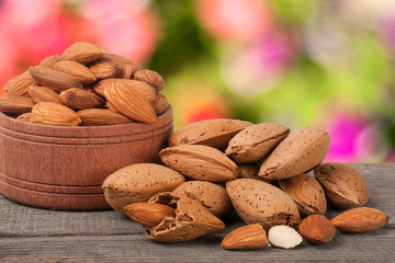 almonds in a bowl on the old wooden board with blurred garden background