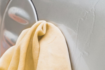 Close up of Male Hand Washing Car with Yellow Chamois (microfiber towel) - Cleaning Concept