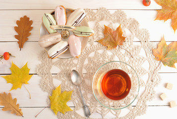 cake in a plate and tea in a transparent mug with spoon and autu
