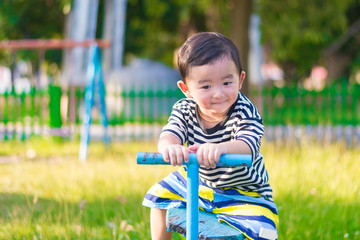 Asian kid riding seesaw board at the playground