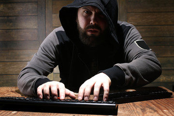 hacker in the black hood in a room with wooden walls