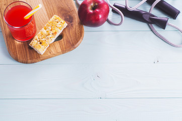 The concept of weight loss, jump rope, juice, cereal bar and red apple, top view. Healthy lifestyle. Fitness Background with copy space. Sport and diet.