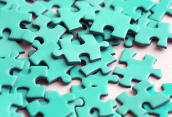 Turquoise puzzle pieces on a white surface.