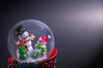 Christmas snow globe with snowman isolated on black background