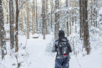 Fototapeta na wymiar Man backpacker walking on a forest road in the winter forest in