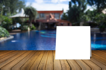 White card put on wooden desk or wooden floor on blurred swimming pool at resort background.use for present or mock up your product.product display template.Business presentation.clipping path include