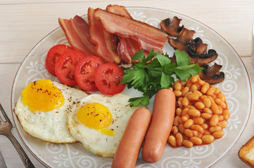 fried eggs with bacon, tomatoes, beans, mushrooms and sausages