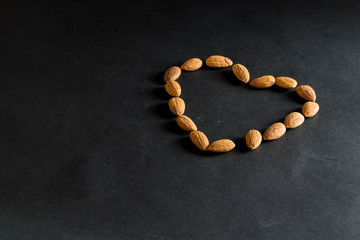 Almond nuts forming a heart-shape on black background