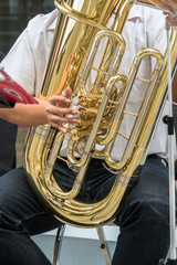 Close up of Hand playing Golden tuba musical instrument, part of