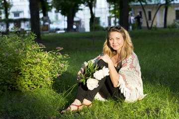 Smiling girl on nature with a bouquet of peonies.The girl outdoors

