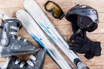 Overhead view of ski accessories placed on rustic wooden table.