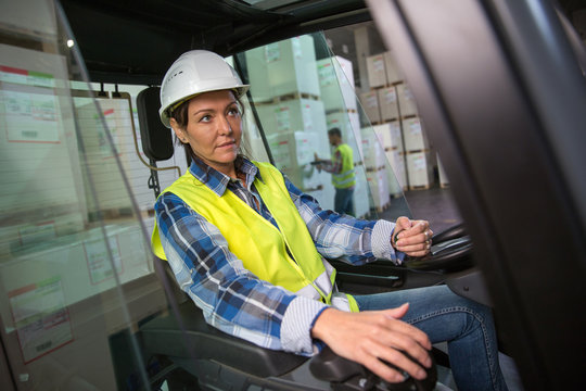 Woman working with a forklift in a warehouse.