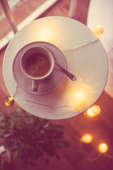 Cup of coffee and warm Christmas lights on a table