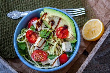 Vegan zucchini pasta in a bowl with tofu, tomatoes, avocado and herbs. Perfect for the detox diet or just a healthy meal.  Love for a healthy raw food concept.
