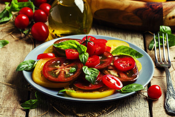 Salad with tomato and basil, old wooden background, selective fo