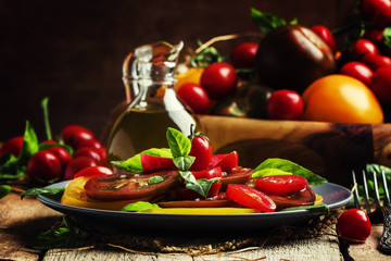 Salad with tomato and basil, old wooden background, selective fo