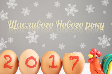 Inscription "Happy new year" in Ukrainian language. Still life with eggs and plasticine cock. Rooster - a symbol of 2017 year. © Stanislaw Mikulski