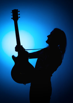 silhouette guitarists of a rock band with guitar on blue background
