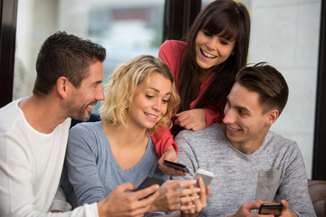 friends looking at smart phones while sitting in cafe