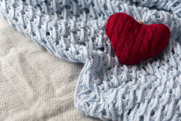 Fototapeta na wymiar knitted red heart on knitted wool blue and gray shawl 