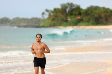 Man athlete running topless in shorts on beach at sunset. Male runner training cardio alone doing exercise on sand with ocean background. Healthy active lifestyle.