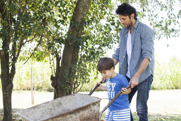 Man teaching young son how to use wheelbarrow