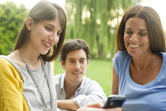 Friends looking at smartphone outdoors