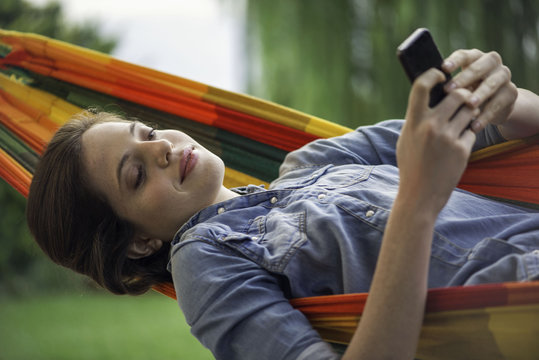 Woman relaxing in hammock with smartphone