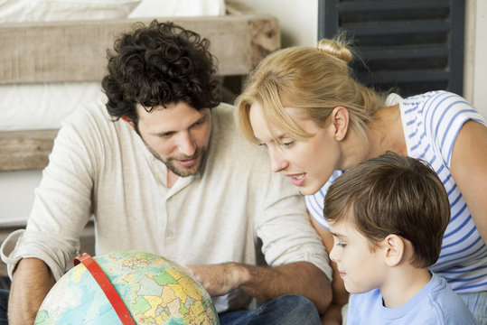 Family looking at a globe while sitting at home