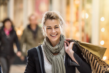 Middle age woman holding shopping bags and walking in the street