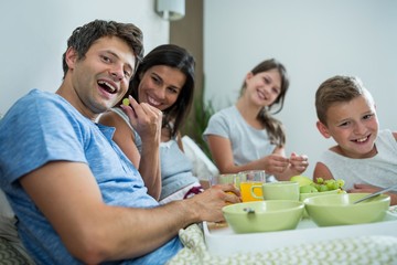 Happy family having breakfast on bed