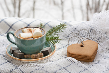 Obraz na płótnie Canvas Christmas concept. Blue mug of hot coffee with marshmallow on a white lace with cookies and Christmas tree branches.