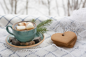 Obraz na płótnie Canvas Christmas concept. Blue mug of hot coffee with marshmallow on a white lace with cookies and Christmas tree branches.