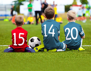 Obraz premium Football Game for Kids. Young Boys Soccer Players Athletes. Children Football Players at Match with Ball. Soccer Bench of Youth Team. Footballers in Red and Blue Sportswear