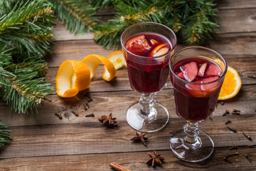 Two glasses of hot mulled wine with oranges, apples and spices