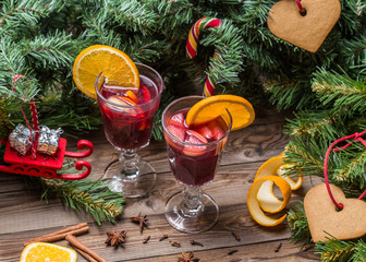 Two glasses of hot mulled wine with oranges, apples and spices
