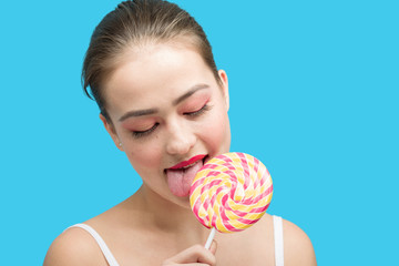 fun girl licks candy on blue background