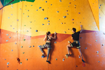 Young man and woman climbing up the wall