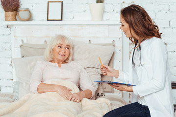 Obraz premium Professional positive female doctor examinig her patient at home
