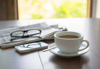Newspaper reading glasses coffee cup and mobile phone on busines