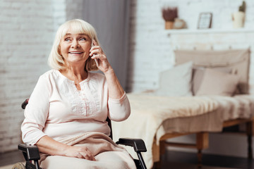 Cheerful disabled senior woman talkign on smart phone