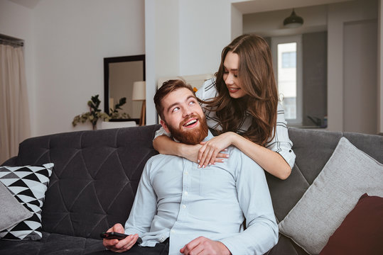 Lady hugging her man while he sitting at sofa