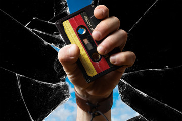 Hand holding old east german Musicassette through broken Glass