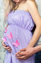 муж и беременная жена держат руки на животе, бабочки. Мама и папа. Беременность