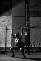 Athletic sporty woman squatting with a long metal bar