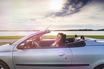 young woman in cabriolet car at lake