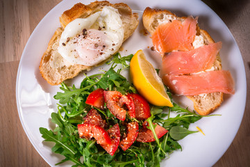 Breakfast plate with two crossants with egg and salmon and side salad